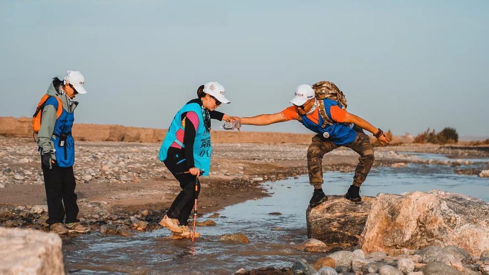 戈壁徒步队员互相协助通过水域